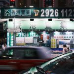A bustling night scene on Mody Road, Hong Kong featuring bright lights and urban activity.