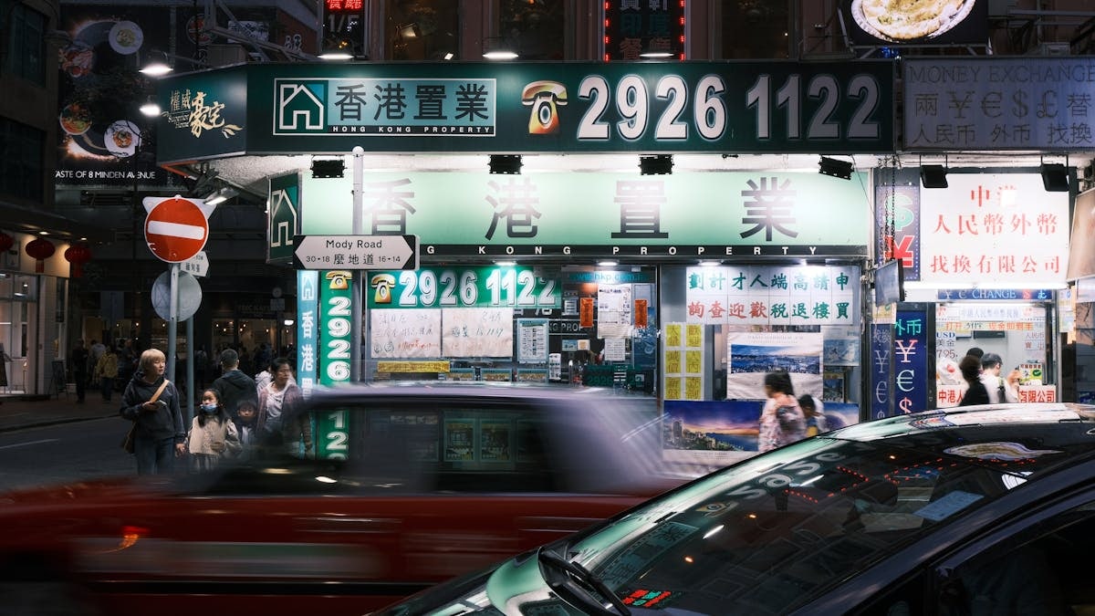 A bustling night scene on Mody Road, Hong Kong featuring bright lights and urban activity.