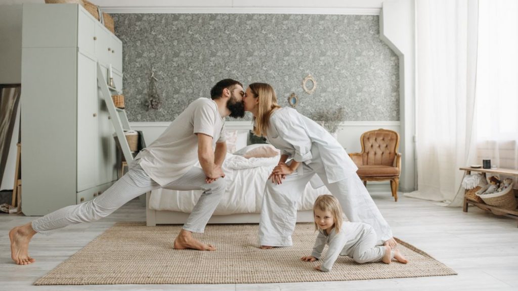 A family enjoying playful bonding moments in a stylish, minimalistic bedroom setting.