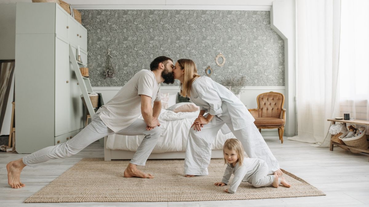 A family enjoying playful bonding moments in a stylish, minimalistic bedroom setting.