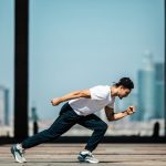 Dynamic shot of a young man sprinting outdoors in an urban setting with skyscrapers in the background.